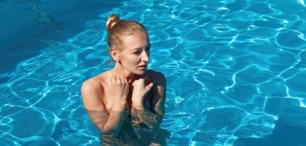 Голая красавица в бассейне наслаждается водой