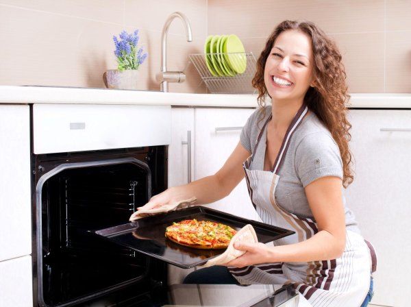 Очаровательная женщина готовит вкусную пиццу на кухне