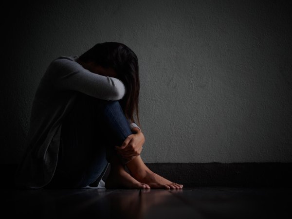 Грустная девушка в эмоциональной позе сидит на полу с печальным взглядом