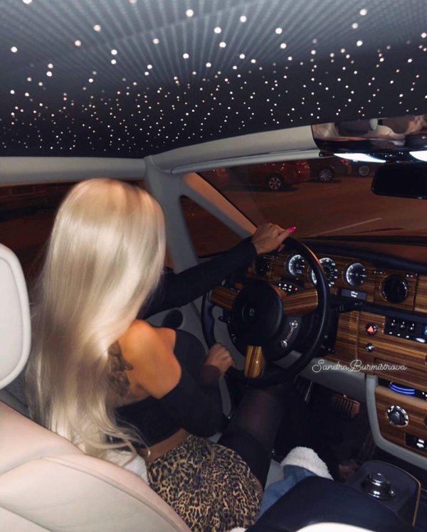 Блондинка в роскошном автомобиле демонстрирует богатство