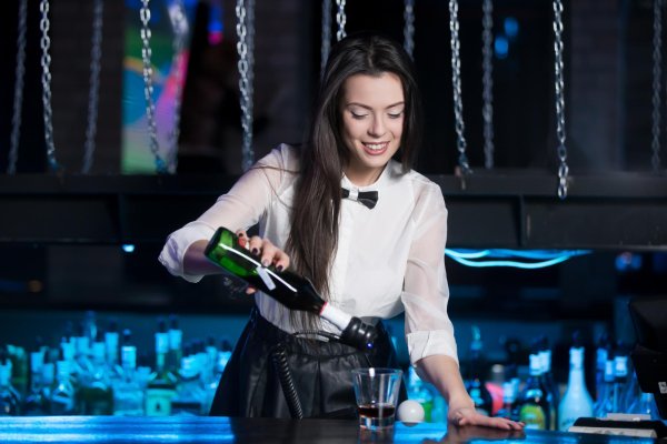 Очаровательная брюнетка бармен работает в уютном баре