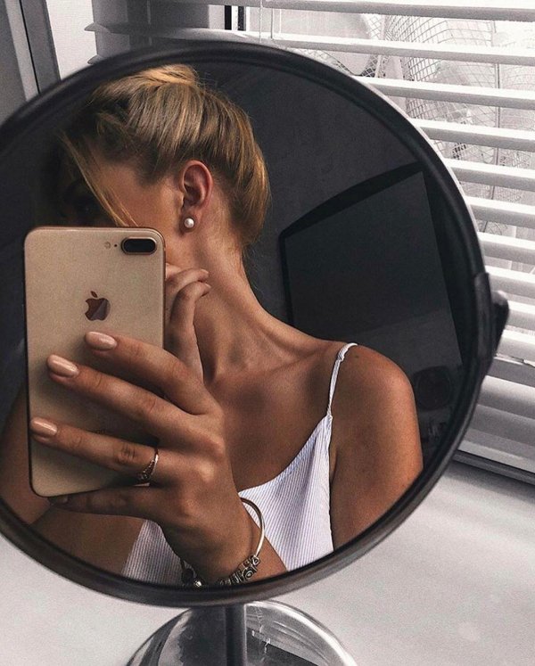 Девушка фоткается у зеркала с айфоном в руке