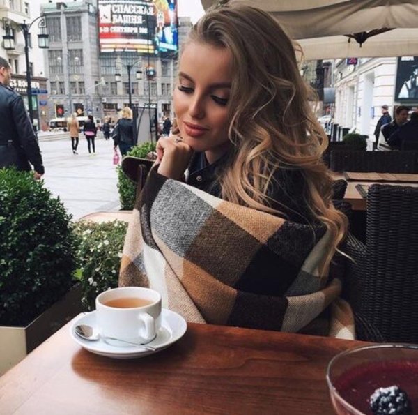 Девушка в пледе с кофе в кафе