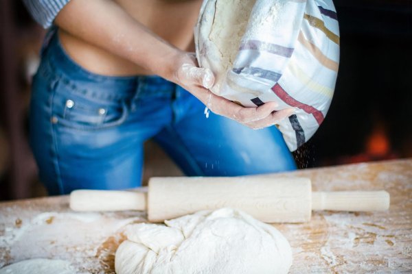 Женщина месит тесто в муке на кухне