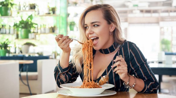 Завораживающая леди аппетитно ест макароны в ресторане