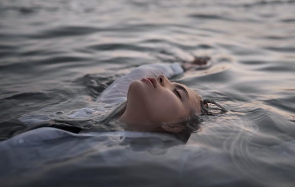 Девушка лежит в воде в привлекательной фотосессии с сексуальными позами