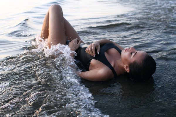 Девушка лежит на воде в сексуальном купальнике с привлекательными позами